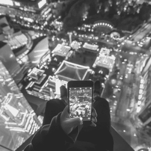 High-angle, black and white view of a city skyline, captured by a smartphone held by two people.